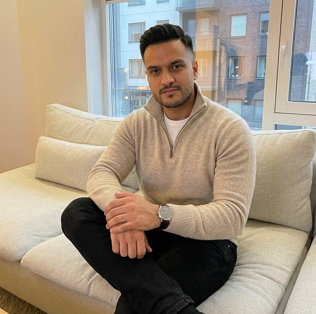 Ray Voice (Author, Business Professional) sitting indoors, wearing an oatmeal sweater and black jeans with an A. Lange & Söhne watch.